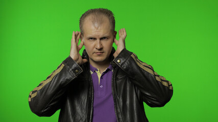Fototapeta premium Don't want listen. Rocker man covering ears with arms not to hear annoying talk, ignoring conflict