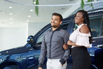 African-American young couple choose a new car at a car dealership, selective focus