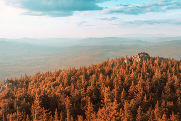 A rocky mountain range covered with forest is illuminated by the pink light of the setting sun. A natural Park or reserve or hunting grounds. Recreational tourism