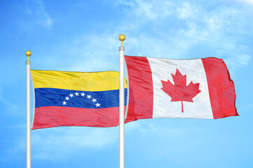 Venezuela and Canada two flags on flagpoles and blue sky