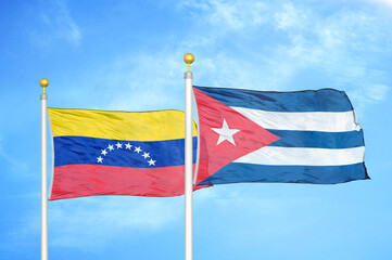 Fototapeta na wymiar Venezuela and Cuba two flags on flagpoles and blue sky