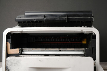 Old laser printer with cartridge on black background, office equipment repair concept