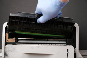 Сoncept of refilling, repairing  laser cartridge,  gloved hand pulls  cartridge out of  printer