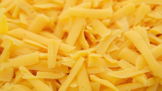 grated cheddar cheese close up, rotating