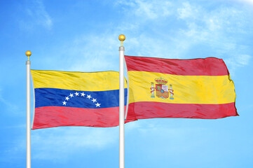 Venezuela and Spain two flags on flagpoles and blue sky