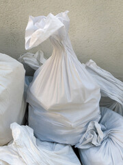 Detail of White debris raffia sack. White Canvas Membrane Plastic Bags With Construction Trash....