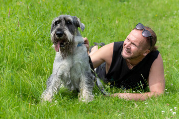 Senior man and his dog lying on the grass in the park.