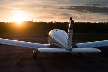 Quadruple aircraft parked at a private airfield. Rear view of a plane with a propeller on a sunset...