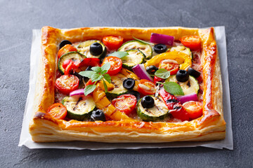 Puff pastry pizza with grilled vegetables. Grey background. Close up.