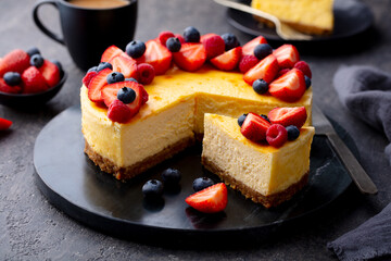 Cheesecake dessrt with fresh berries and cup of coffee. Gray background. Close up.