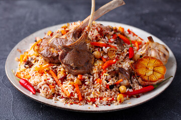 Traditional pilaf, plov with rack of lamb. Grey background. Close up.