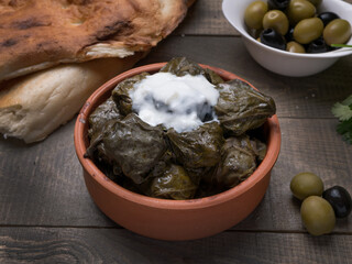 Traditional azerbaijan dolma in grape leaves on rustic wooden table with copyspace.  Oriental dish .  Traditional georgian tolma in vine leaves on rustic background with copyspace. Turkish dish