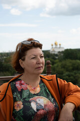 a woman in an orange sweater admires the panoramic views of the city from the observation deck of a tall ancient tower