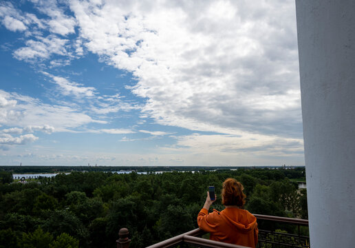 a woman in an orange sweater admires the panoramic views of the city from the observation deck of a tall ancient tower