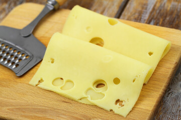 Slices of tasty Swiss cheese on wooden board
