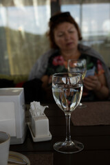 reflection of a woman at the table in a glass of white wine