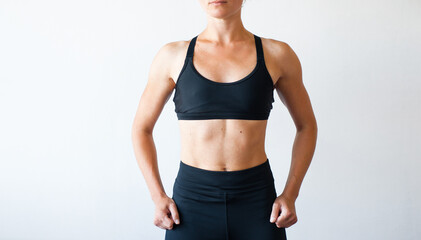 Beautiful sporty woman in black  leggings posing on grey background. Photo of girl with slim toned body. Beauty and body care concept