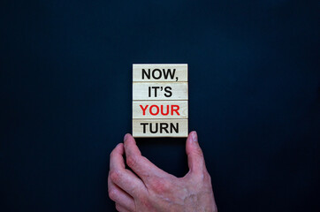 Wooden blocks form the words 'now, it's your turn' on beautiful black background. Male hand. Beautiful background. Business concept.