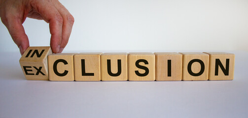 Symbol for a better inclusion. Hand turns cube and changes the word exclusion to inclusion. Beautiful blue background. Business concept, copy space.