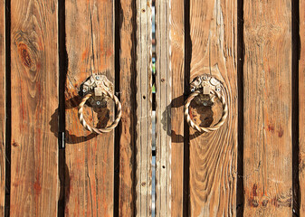 Fragment of a wooden gate with forged metal handles in the form of rings