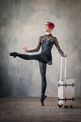 young ballerina in a black suit and black pointe shoes, dancing against the background of a...