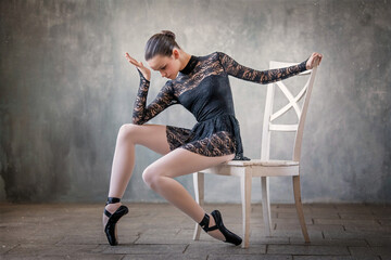 young ballerina in a black suit and black pointe shoes, dancing against the background of a...