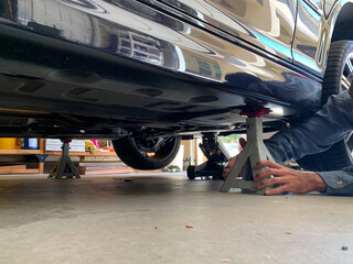 Mechanic Placing Jacks Under Car to Lift it to Perform Maintenance