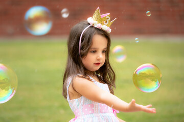 3-year-old birthday girl playing with soap bubbles  outdoors