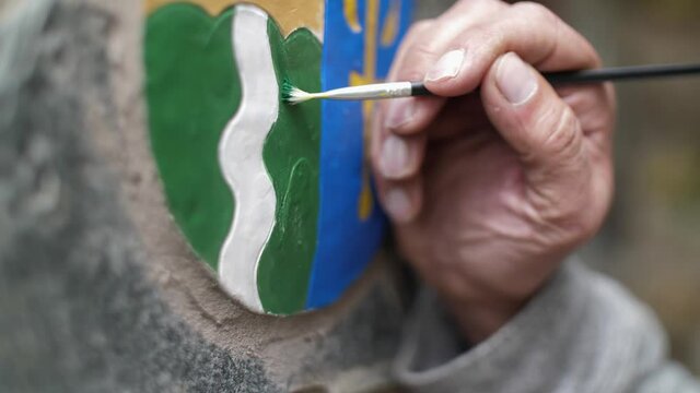 Man painting a coat of arms emblem of a small Czech village in Ore Mountains region
