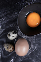 Egg yolk in a bowl with quail eggs next to the eggs outside or inside the bowl