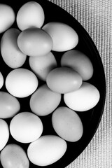 A black-and-white image of a close-up of a number of eggs in a container.