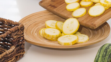 Sliced zucchini close up on wooden plate on white background