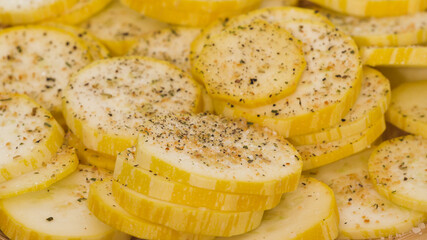 Zucchini slices on a plate, seasoning with garlic salt and fresh ground pepper