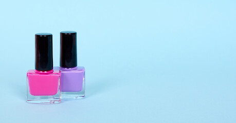 Colors nail polish bottles, make up. Isolated on blue background. Copy space.