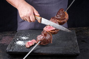 Traditional barbecue dry aged wagyu Brazilian picanha from the sirloin cap of rump beef sliced by a...