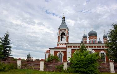 Fototapeta na wymiar Beautiful bell tower of an Orthodox Church against a cloudy blue sky.
