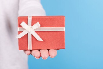 Hand with red gift box. Isolated on blue background.
