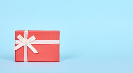 Red gift box with ribbon. Isolated on blue background, copy space template, banner.