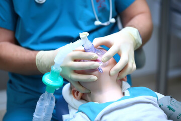 The anaesthetist holds a breathing mask on the child's face.Preparation for dental surgery. Treatment of multiple caries of baby teeth. The device of artificial ventilation of lungs. 