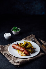 Pork sausage baked with green bell peppers, onion and herbs on white plate