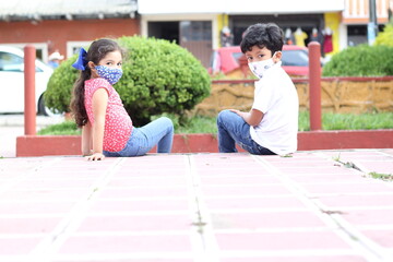 6-year-old boy and girl with protective face masks for virus covid-19, in the park, new normal