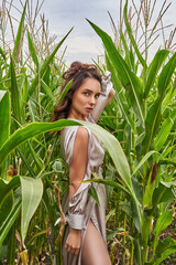 Beautiful sexy girl in dress in green leaves in cornfield. Fashion/vogue concept