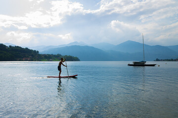 Naklejka premium A young man standing up paddle board in Lake Orta, Italy