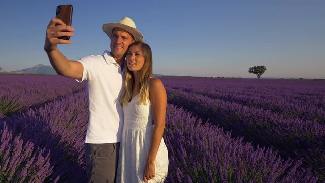 Slow motion - Couple taking selfies with smartphone in lavender field at sunset, Provence
