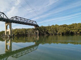Beautiful view of a river with reflections of tall pedestrian bridge, trees and blue sky, Parramatta river, Rydalmere, New South Wales, Australia