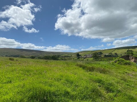 High on the hills, above Wycoller, with grass, wild plants, farm buildings and distant moors near, Wycoller, Colne, UK