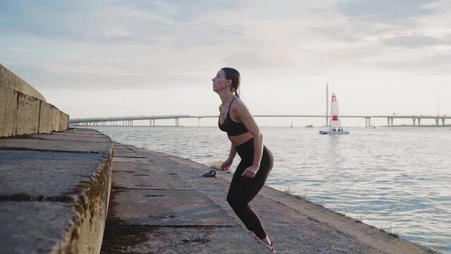 Fitness woman doing a workout at the sunset. Slow motion footage of Muscular female doing Box jump. Determined fitness girl focused on getting stronger. Active and sport concept.