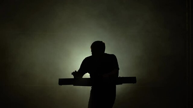 Musician silhouette playing on synthesizer piano keyboard in dark studio with neon lighting. Dynamic neon lighting effects. Performance vocal and musical band.