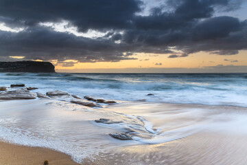 Sunrise at the beach with waves and clouds