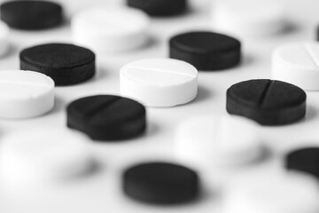 Obraz na płótnie Canvas Close up of black and white pills lie exactly in a row on a white table. Isolated pharmaceutical drug background